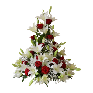 En blomsterarrangemang med vita liljor och röda rosor, dekorerat med små vita blommor och gröna blad.