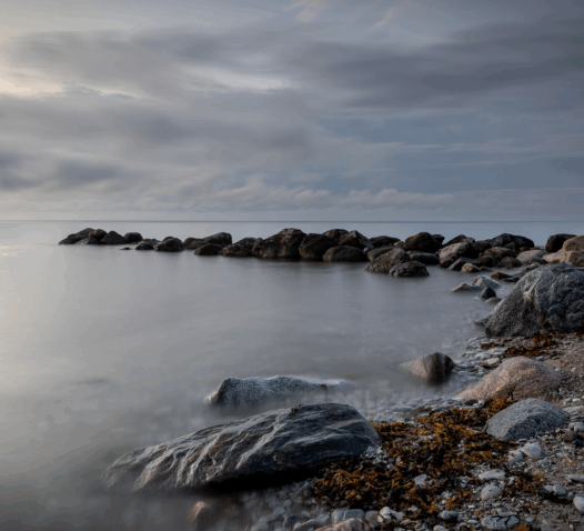 Steniga kustlinjer under en molnig himmel vid havet.